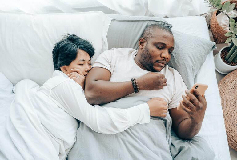 a Couple Lying in Bed While the Wife Fails to Catch the Cheater's Texting