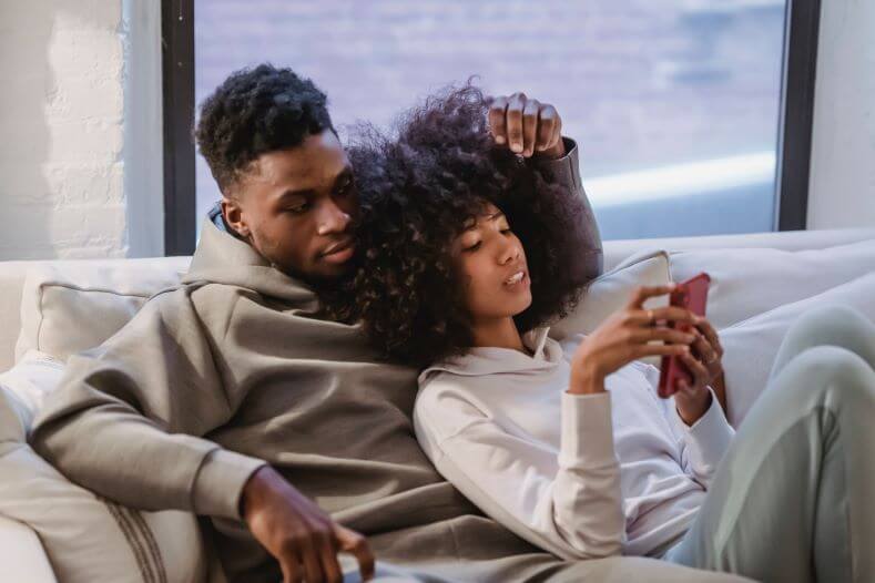 Couple Sitting on the Sofa and Showing How to Read Cheating Spouse's Text Messages for Free