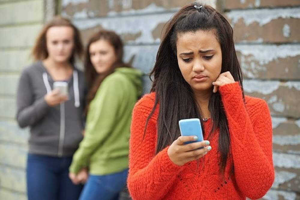 Girl in Orange Looking at Cellphone