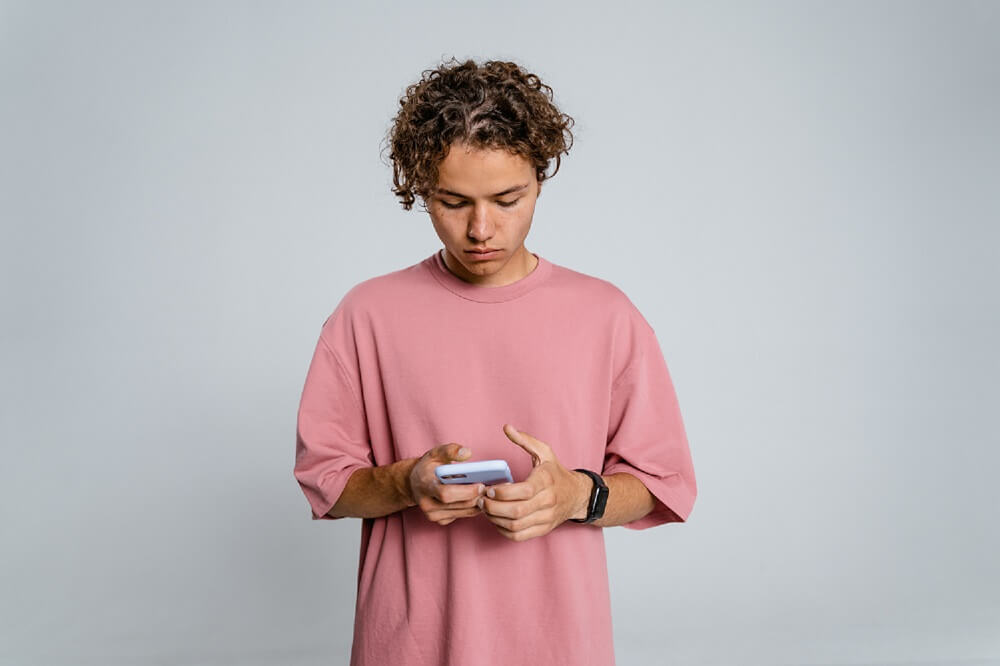 Man in Pink Looking at Cellphone