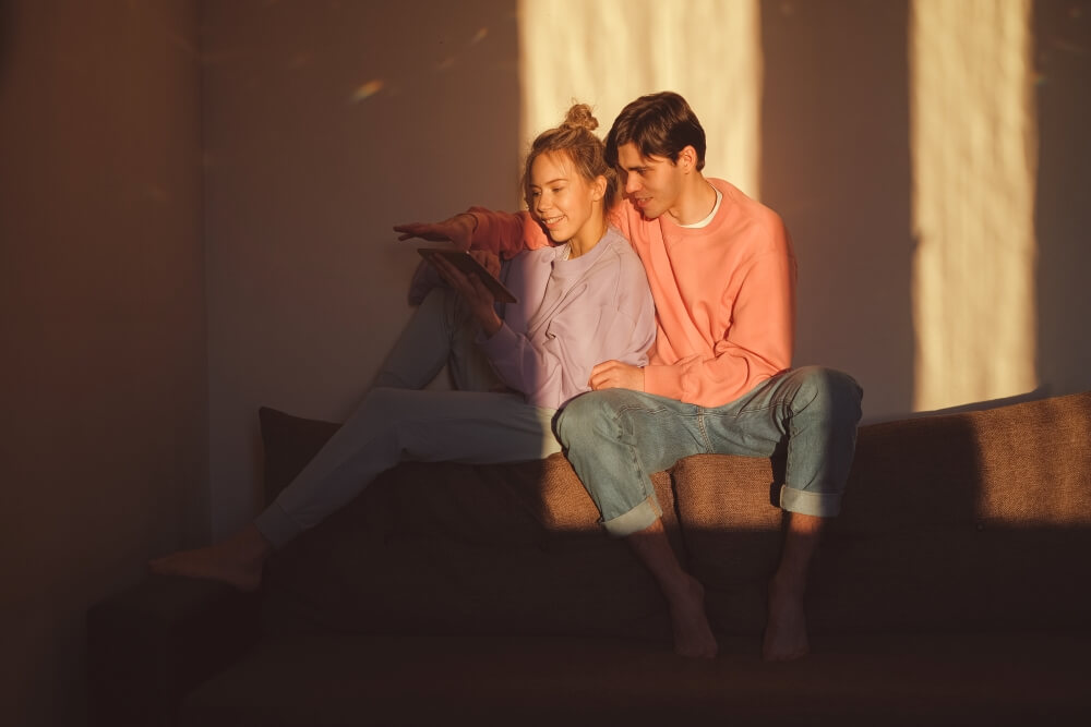 Two People Sitting on A Sofa with One of Them Thinking about How to Hack A Phone