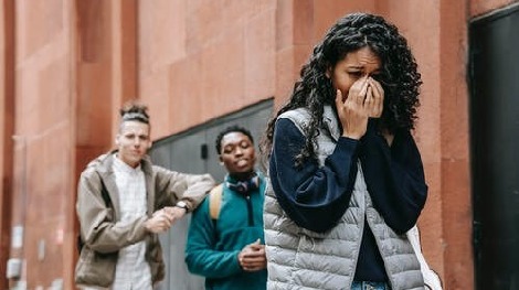 Two men mocking a woman burying her face in her hands whose parents need to know how to tap a phone to protect her